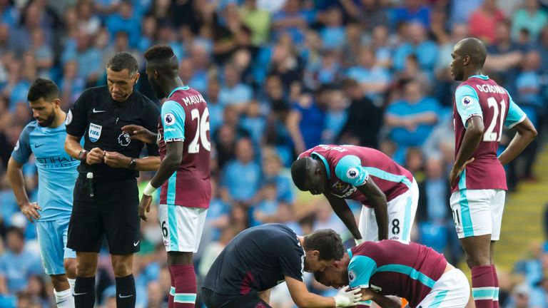 West Ham United's New Zealand defender Winston Reid, (2nd R), is treated after a clash with Manchester City's Argentinian striker Sergio Aguero (L) 