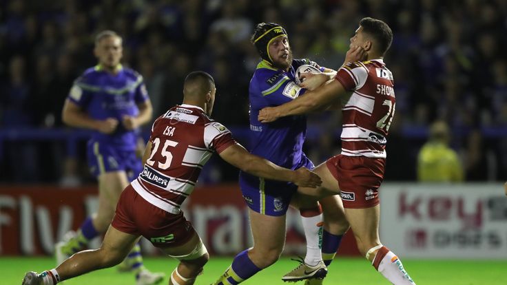 Warrington Wolves' Chris Hill is tackled by Wigan Warriors Willie Isa (left) and Jake Shorrock (right)