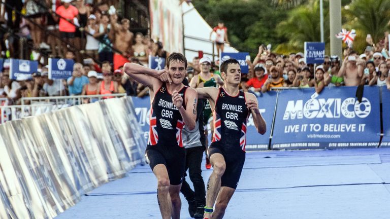 British athlete Alistair Brownlee (L) helps his brother Jonathan Brownlee (R) before crossing the line during the ITU World Championship