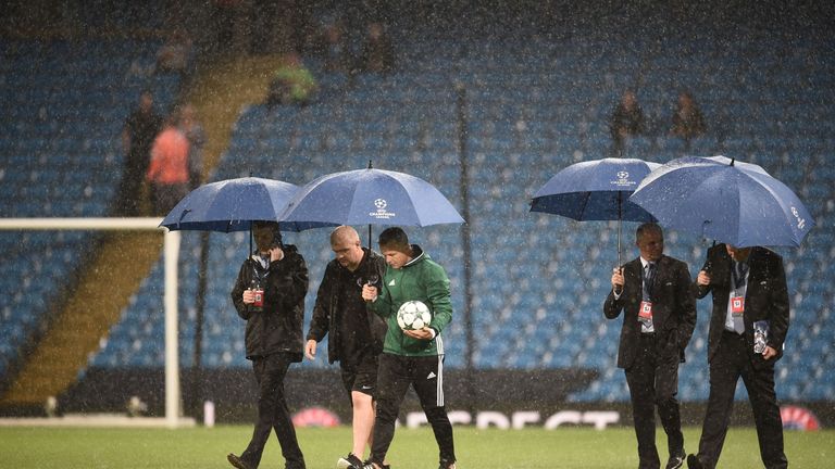 Officials inspect the pitch as heavy rain continues to pour ahead of the Champions League Group C match between Man City and Borussia Monchengladbach