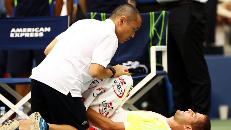 NEW YORK, NY - SEPTEMBER 02:  Mikhail Youzhny of Russia is tended to by the trainer against Novak Djokovic of Serbia during his third round Men's Singles m