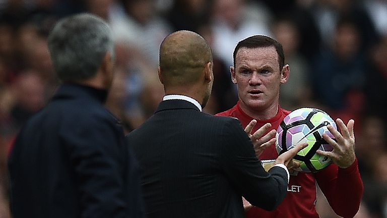 Manchester United's English striker Wayne Rooney (R) and Manchester City's Spanish manager Pep Guardiola clash on the touchline as Rooney tries to retrieve