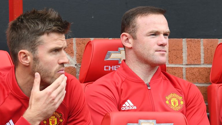 Wayne Rooney (R) sits on the substitutes bench Michael Carrick