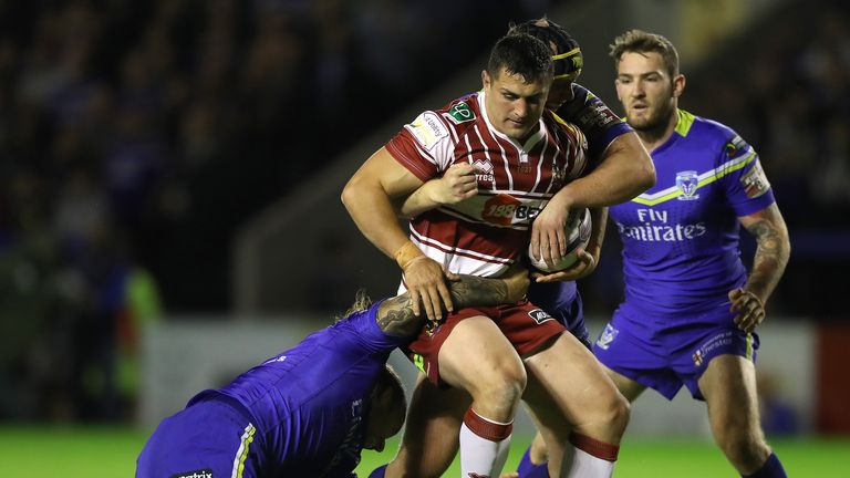 Wigan Warriors Ben Flower is tackled by Warrington Wolves' Ashton Sims (left) and Chris Hill (right)