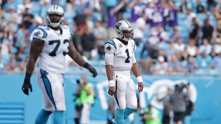 Cam Newton cuts a dejected figure as he walks off the field with team-mate Michael Oher