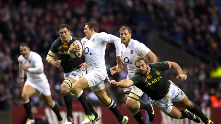 England's full back Alex Goode (C) tries to break a diving tackle from South Africa's prop Jannie du Plessis (R) during the International rugby union match