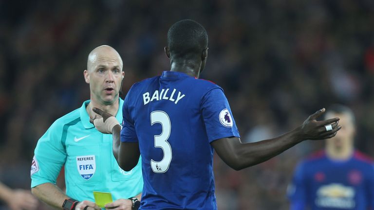 Referee Anthony Taylor issues a yellow card to Manchester United's Eric Bailly at Anfield