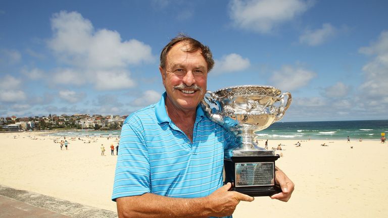 Former tennis player John Newcombe poses with the Norman Brookes Challenge Cup (men's singles trophy) during the Australian Open