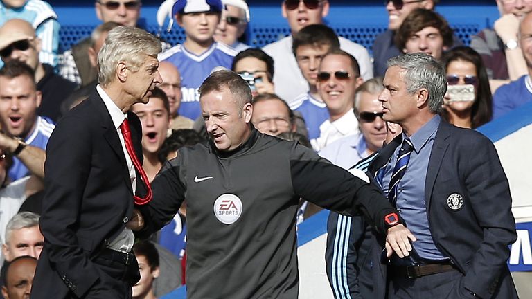Chelsea's Portuguese manager Jose Mourinho (R) and Arsenal's French manager Arsene Wenger (L) are kept apart by the fourth official Jonathan Moss.