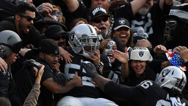 OAKLAND, CA - NOVEMBER 27:  Khalil Mack #52 of the Oakland Raiders celebrates in the stands after scoring on an interception of Cam Newton #1 of the Caroli