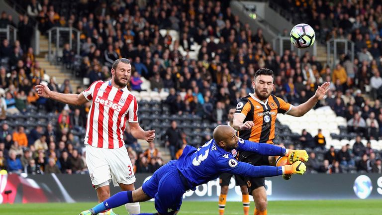Lee Grant of Stoke City (C) attempts to punch the ball before Robert Snodgrass of Hull City (R) can get to it 
