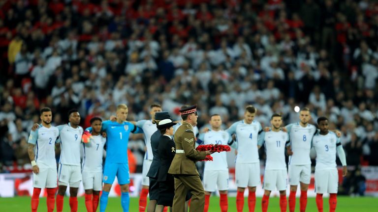 Members of the Armed Services carry a Poppy wreath onto the pitch as England players look on in remembrance of Armistice Da