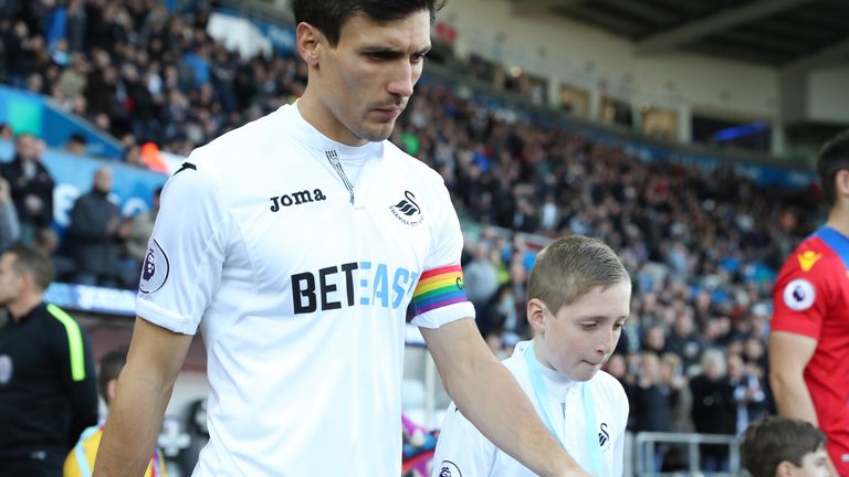 SWANSEA, WALES - NOVEMBER 26: Jack Cork of Swansea City weariing a rainbow colour captain's arm band enters the pitch prior to the Premier League match bet
