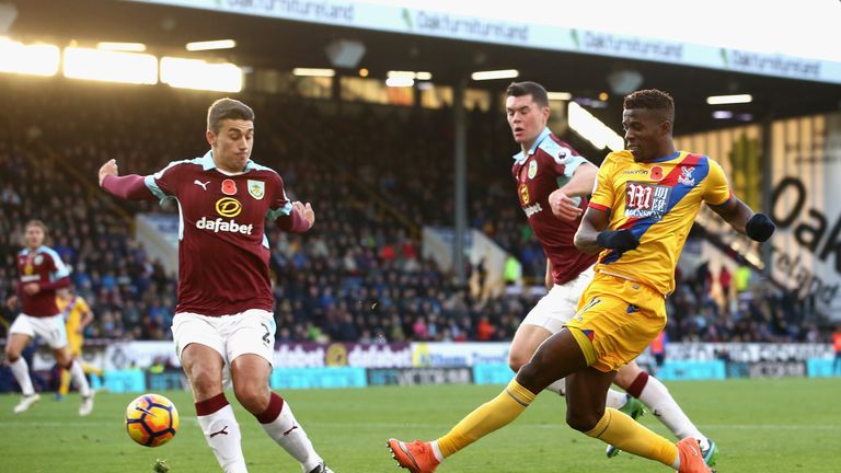 Wilfried Zaha crosses while Matthew Lowton attempts to block during the Premier League