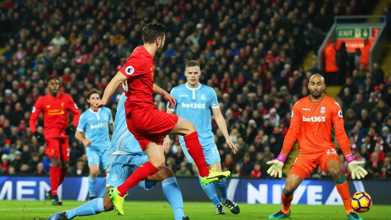 Adam Lallana of Liverpool shoots past Lee Grant of Stoke City to score their first goal during the Premier League match at Anfield