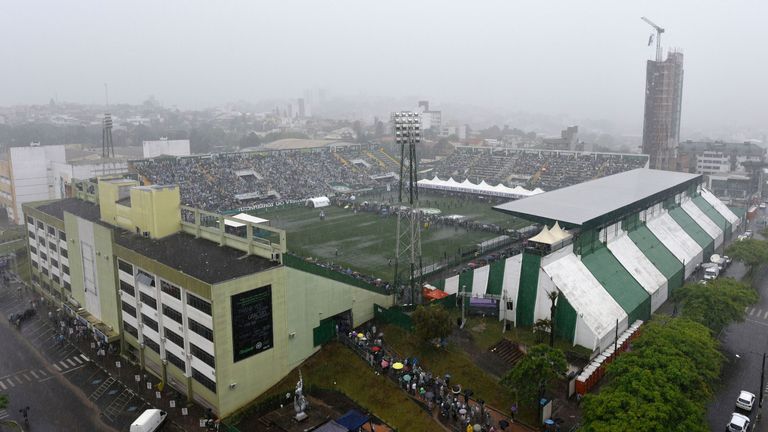 People line up under heavy rain to enter the already crowded stadium where the coffins of the members of the Chapecoense Real football club team killed in 