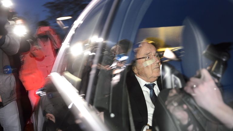 Suspended FIFA president Sepp Blatter reacts in his car surrounded by journalists leaving the world football's governing body headquarters on December 17, 