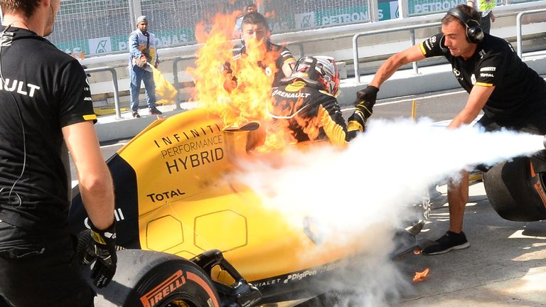 A fire from Kevin Magnussen's Renault car is extinguished in the Sepang pitlane - Pictures from Sutton Images 