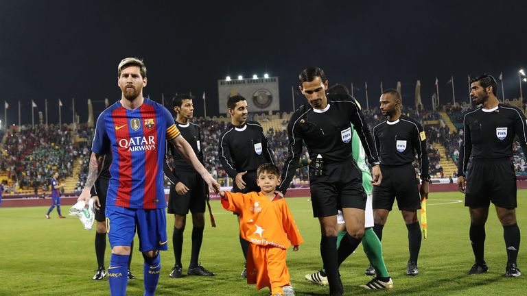 Lionel Messi holds the hands of Afghan boy Murtaza Ahmadi on the pitch before a friendly