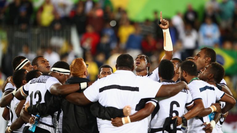 Fiji players and staff huddle after winning gold at the Rio Olympics