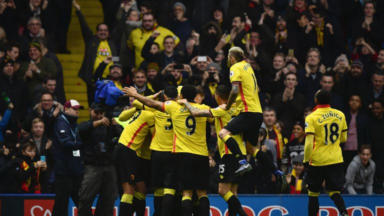 Stefano Okaka of Watford (obscured) celebrates with team mates and fans as he scores their third goal during the Premier League