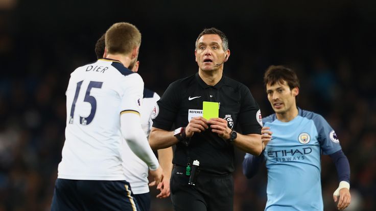 Eric Dier of Tottenham Hotspur (L) is shown a yellow card by referee Andre Marriner during the Premier League match between Manchester City and Tottenham