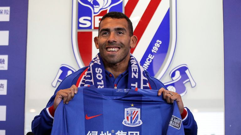Carlos Tevez poses with a jersey during a press conference for new club Shanghai Shenhua