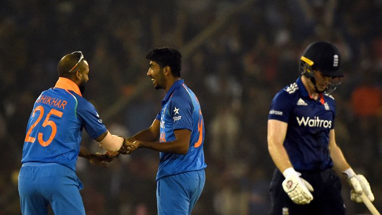 England's captain Eoin Morgan (R) walks back to the pavillion as India's Jasprit Bumrah (2L) celebrates his wicket with Shikhar Dhawan during the second On