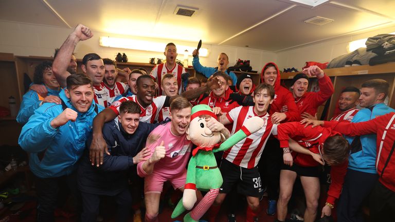 Lincoln City players celebrate in the dressing room after knocking Ipswich out of the FA Cup