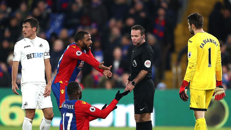 Referee Paul Tierney speaks to Christian Benteke of Crystal Palace after being gone down by Lukasz Fabianski of Swansea City