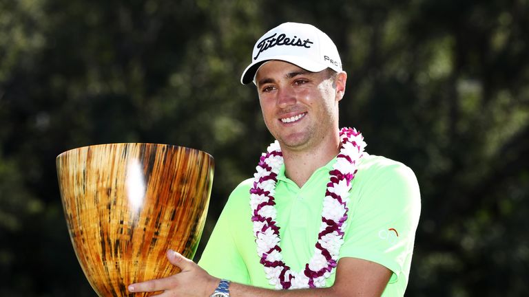 Justin Thomas celebrates with the trophy on the 18th green after winning the SBS Tournament of Champions