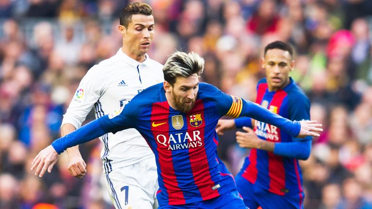Barcelona's Lionel Messi holds off a challenge from Cristiano Ronaldo of Real Madrid