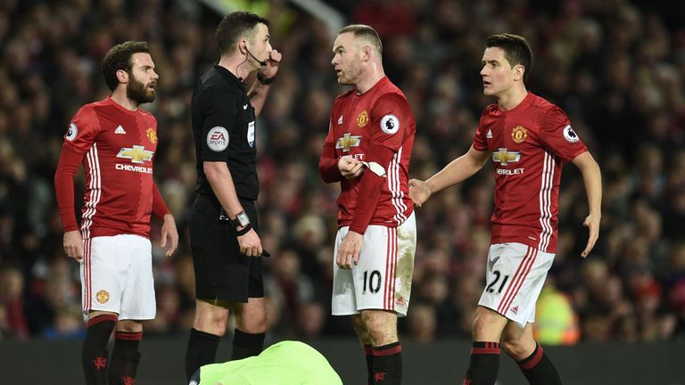 English referee Michael Oliver (2L) talks with Manchester United's Wayne Rooney (2R) following his challenge on James Milner of Liverpool