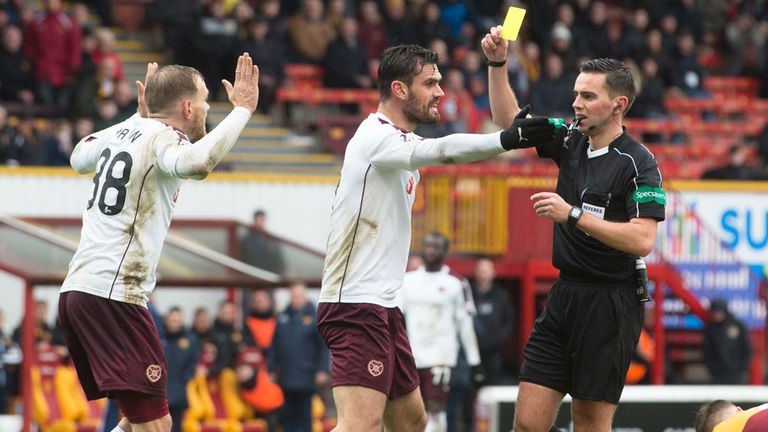 Hearts midfielder Malaury Martin (L) is booked by referee Andrew Dallas