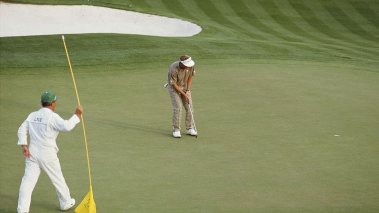 Caddy Dave Musgrove looks on as Sandy Lyle of Great Britain holes out his putt on the final 18th hole to win the US Masters Golf Tournament on 10th April 1