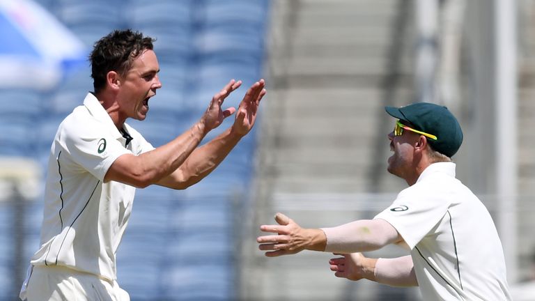 Australia's Steve O'Keefe (L) celebrates with teammate David Warner after the dismissal of India's Wriddhiman Saha during the second day of the first crick