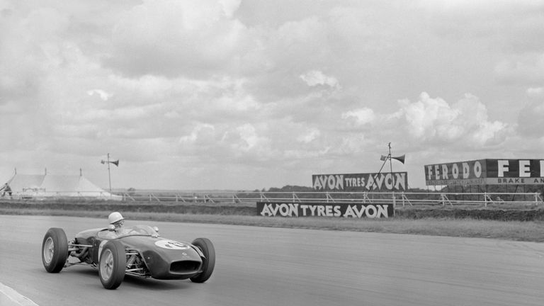 John Surtees, World Champion racing motorcyclist at the wheel of a Team Lotus car as he sped around the Silverstone circuit during practice for the 13th RA