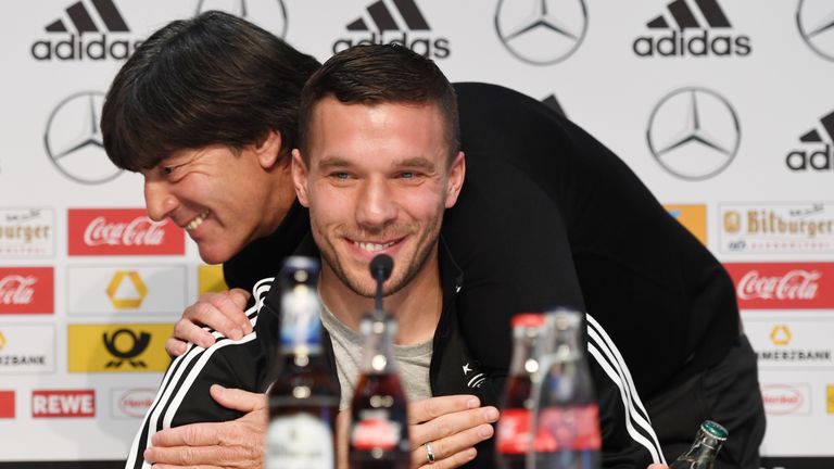 Germany's midfielder Lukas Podolski smiles as Germany's head coach Joachim Loew gives him a hug, during a joint press conference in Dortmund, western Germa