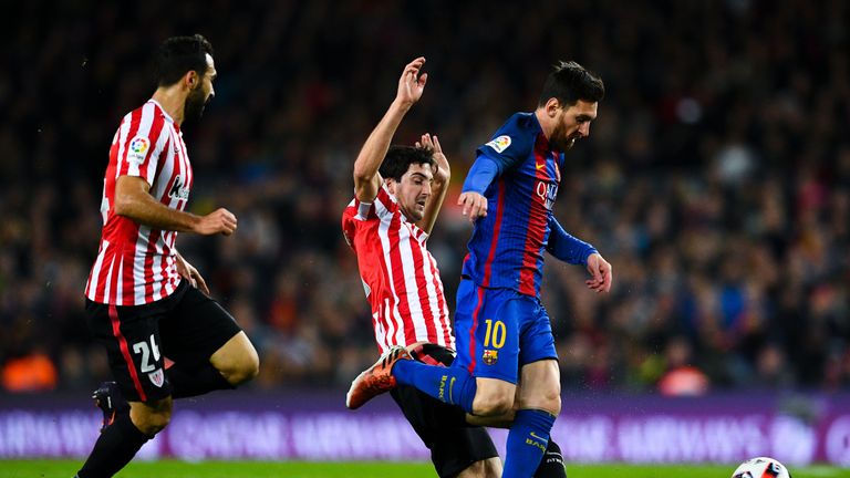 Mikel San Jose tackles Barcelona's Lionel Messi during a game at the Nou Camp