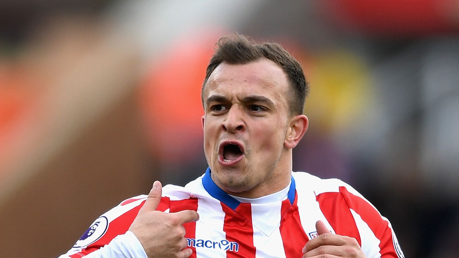  Xherdan Shaqiri is pictured playing for Stoke City in a red and white striped jersey, white shorts, and red socks.