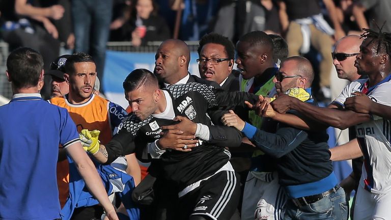 A security staff holds Lyon's goalkeeper Anthony Lopes (C) during scuffles at half-time between some of Lyon's players and Bastia supporters who invaded th