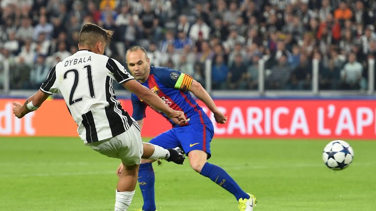 Juventus' forward from Argentina Paulo Dybala (L) scores against Barcelona's midfielder Andres Iniesta during the UEFA Champions League quarter final first