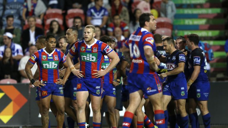 Knights players look dejected with Bulldogs celebrating in the background