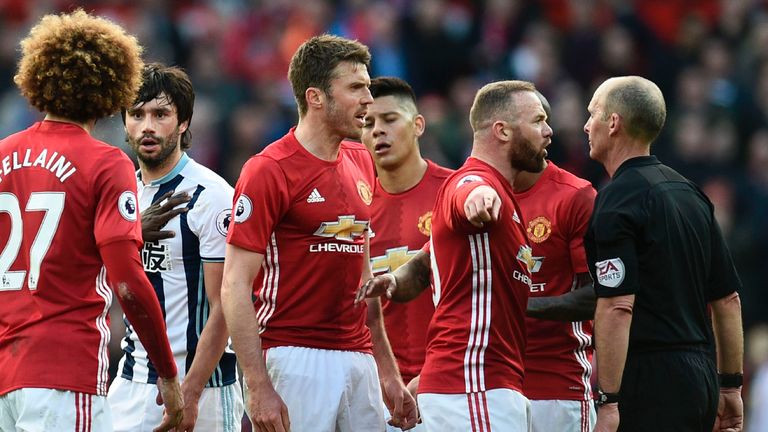 Manchester United's English striker Wayne Rooney (2R) and Manchester United's English midfielder Michael Carrick (3R) talk with referee Mike Dean (R) durin