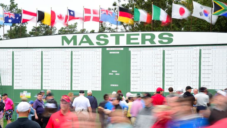 Patrons walk past a leaderboard next to the first fairway during a practice round prior to the start of the 2017 Masters Tournamen