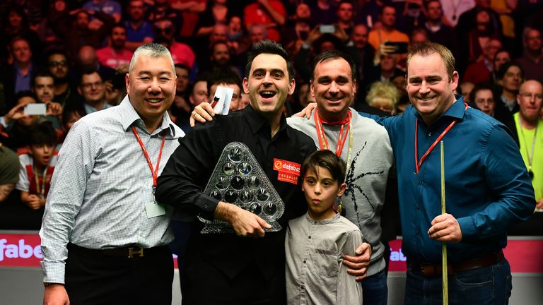 Ronnie O'Sullivan of England celebrates with the Paul Hunter Trophy alongside his team following victory during the Masters final