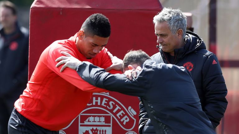 Chris Smalling stretches with Wayne Rooney as Jose Mourinho looks on