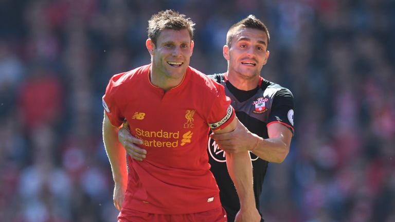 Liverpool's English midfielder James Milner (L) is held by Southampton's Serbian midfielder Dusan Tadic 