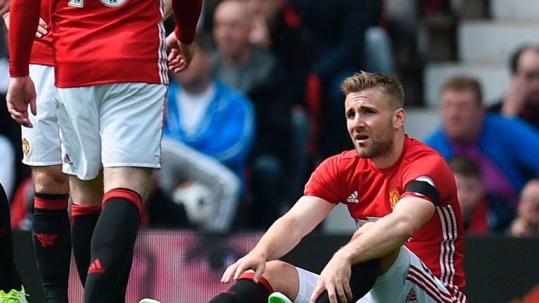 Manchester United's English defender Luke Shaw (R) sits injured on the pitch during the English Premier League football match between Manchester United and