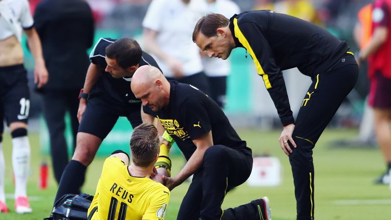Marco Reus receives treatment as Borussia Dortmund head coach Thomas Tuchel looks on